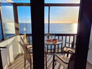 a table and chairs on a balcony with the ocean at Very Romantic Seaview Apartment Patalavaca Mogán with Warm Pool in Patalavaca