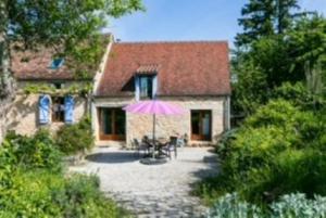 a house with a pink umbrella in front of it at Gîtes Oasis du Lot in Payrac