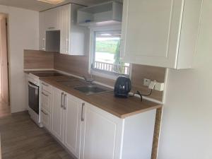 a kitchen with white cabinets and a sink and a window at Mobilheim Výr in Výrovice +17 photos