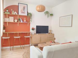 a living room with a couch and a tv at Écrin Terracotta in Clermont-Ferrand