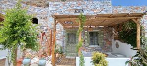 a stone house with a porch and a stone wall at Aliori art caves in Aegiali