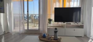 sala de estar con TV de pantalla plana en un centro de entretenimiento blanco en Apartamento en Salou-Vistas al Mar, en Salou
