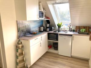 a small kitchen with white cabinets and a sink at Luett Huus in Eckernförde