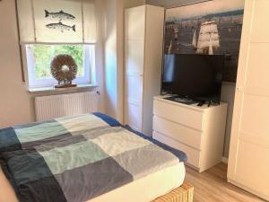 a bedroom with a bed and a flat screen tv at Luett Huus in Eckernförde