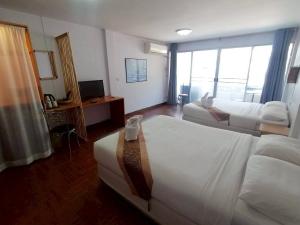 a hotel room with two beds and a television at Beachfront Hotel Cha Am in Cha Am