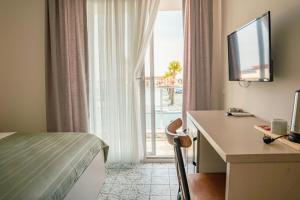 a hotel room with a bed and a desk and a window at Koi otel in Ayvalık