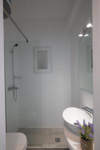 a white bathroom with a toilet and a shower at Mykonos Townhouse Gem in Mýkonos City