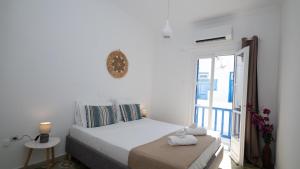 a white bedroom with a bed and a balcony at Mykonos Townhouse Gem in Mýkonos City
