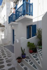 a woman sitting on a balcony with blue doors and plants at Mykonos Townhouse Gem in Mýkonos City