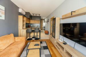 a living room with a couch and a large tv at Harizma apartmani - Astera in Kragujevac