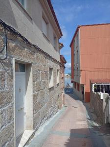 kamienny budynek z białymi drzwiami na ulicy w obiekcie Casa O Vento w mieście O Grove