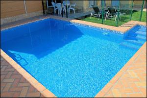 einen großen blauen Pool mit einem Tisch und Stühlen in der Unterkunft Bungalow Curro Pareja 131 in Conil de la Frontera