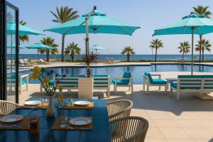 スースにあるSousse Pearl Marriott Resort & Spaのテーブルと椅子のあるレストラン、スイミングプールを提供しています。