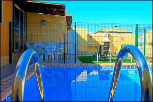 una piscina con una valla, mesas y sillas en Bungalow Curro Pareja 131, en Conil de la Frontera
