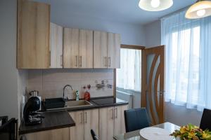 a kitchen with wooden cabinets and a sink and a table at Orchidea apartman in Makó