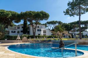 a swimming pool with a resort in the background at Luxury Beach House Apartment - Golf & Tennis Court & Pool View in Albufeira