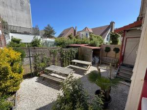 ein Garten mit zwei Bänken und einem Zaun in der Unterkunft Riquette in Le Touquet-Paris-Plage
