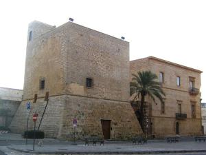 a large brick building with a palm tree in front of it at Corte Merlata Apartments in Galatone