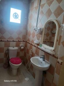 Un baño con inodoro, lavabo y espejo. en العييري للشقق المخدومة الدمام 3, en Dammam 8 fotos más