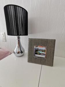 eine Lampe auf einem Tisch neben einem Bilderrahmen in der Unterkunft Chambre Indépendante "Terre Rouge" in Martignas-sur-Jalle