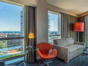 a living room with a couch and a chair and a glass table at Novotel Barcelona City in Barcelona