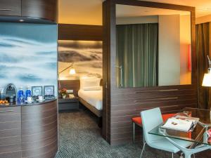 a hotel room with a bed and a desk and a table at Novotel Barcelona City in Barcelona
