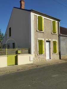a white house with green shutters on a street at Chambre agréable au fond du jardin in Sancoins