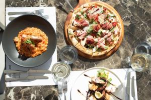 a table with a pizza and a plate of food at Porto Plomari in Plomari