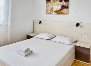 1 cama blanca en un dormitorio con una foto en la pared en Plutus Sea View Apartment, en Sarandë