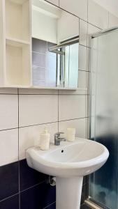 Un baño con un lavabo blanco y un espejo. en Plutus Sea View Apartment, en Sarandë