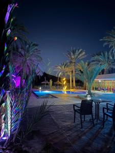 拉希迪耶Hotel Kasbah Fenguig的庭院,晚上有椅子和棕榈树