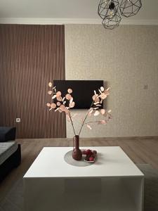 a vase with flowers on a table in a living room at Apartman Tara in Subotica