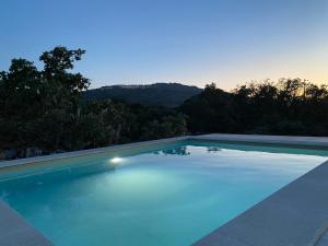 a blue swimming pool with a mountain in the background at Vale Penedo in Santo António das Areias