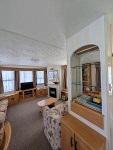 Isle of WightにあるBembridge Hideaway Static Caravan - Sandhills Holiday Park with Private Beachのソファと鏡のあるリビングルーム