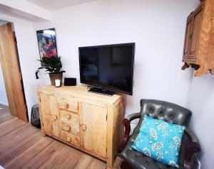 a tv sitting on top of a wooden cabinet with a chair at Gorgeous Apartment near Bournemouth Beach in Bournemouth