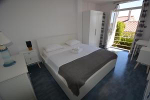 a white bedroom with a bed and a window at Sunny Cottage in Petrcane