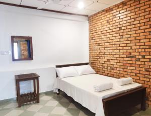 ein Schlafzimmer mit einem Bett und einer Ziegelwand in der Unterkunft Chandra Holiday Home in Dikwella