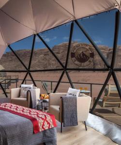 a tent with two beds and chairs and a table at WADI RUM DESERt MOON in Wadi Rum