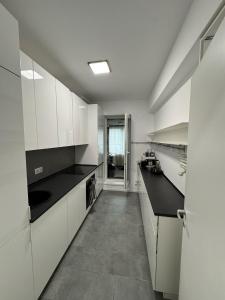 eine Küche mit weißen Schränken und schwarzen Arbeitsplatten in der Unterkunft Resort Vibes in Bucharest Atria 2BR Pool Parking in Bukarest