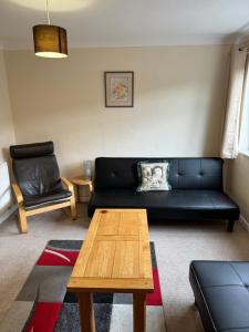 a living room with a black couch and a coffee table at Quiet, Sleeps 12, 2 bathrooms, Lots of parking, KIA 2 in Nottingham