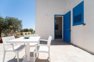 a white table and chairs on a patio with a blue door at Villa Gioiello CENTRO in Favignana