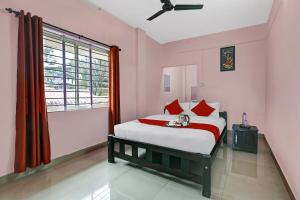 a bedroom with a bed with red pillows and a window at Hotel O Valley View Residency in Vagamon