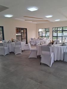 a dining room with white tables and white chairs at Kalundu Conference Centre in Lusaka +8 photos