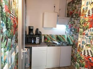 eine kleine Küche mit weißen Schränken und einer bunten Wand in der Unterkunft 1-ZApp "TRENDHAUS-1" Zentrum! in Hofgeismar