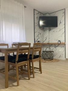 ein Holztisch mit Stühlen und ein Fernseher an der Wand in der Unterkunft El Rincón de Elena II in Cazorla