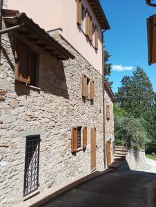 a stone house with wooden windows and a road at OLEA casa vacanze in Todi