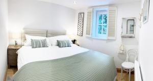 a white bedroom with a bed and a window at The Stables at The Forge Self Contained Apartment in Pyecombe