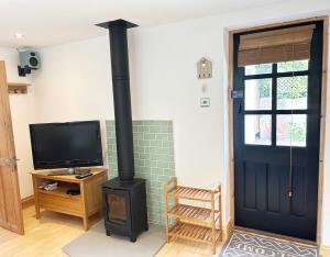 a black stove in a room with a tv and a door at The Stables at The Forge Self Contained Apartment in Pyecombe