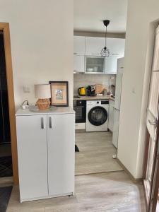 een keuken met witte kasten en een wasmachine en droger bij Deluxe studio beach Lazur in Boergas