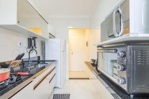 uma cozinha com um fogão e um lavatório em Apartamento Praia Enseada - Guarujá no Guarujá